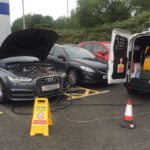 Busy UK motorway service station with cars refuelling.